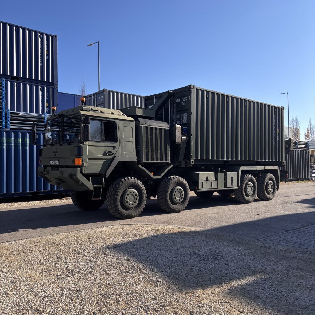Új, egyutas 20’ NATO-zöld raktárkonténer mozgatása a rakodás során – katonai felhasználásra készítve